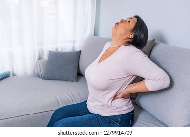 Senior Woman Suffering From Backache At Home. Lower Back Pain In Elderly Person. Woman Feels Back Pain Massaging Aching Muscles, Sad Senior Older Lady Suffers From Low-back