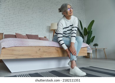 Senior Woman Suffering From Leg Pain While Sitting On The Bed At Home