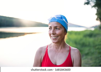 Senior Woman In Swimsuit Standing By Lake Outdoors Before Swimming.