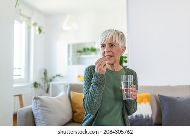 Senior Woman Takes Pill With Glass Of Water In Hand. Stressed Female Drinking Sedated Antidepressant Meds. Woman Feels Depressed, Taking Drugs. Medicines At Work