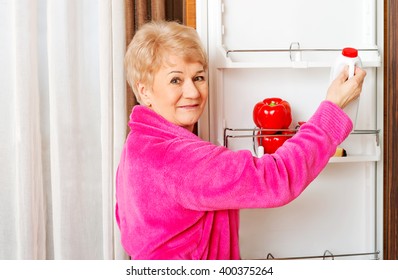 Senior Woman Taking A Bottle Of Milk From Fridge