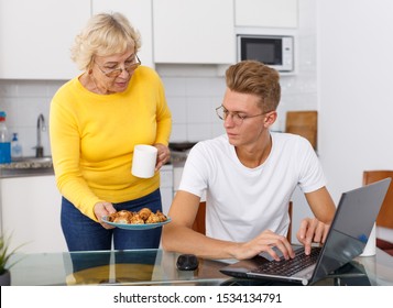 Senior woman taking care of her adult son and serving him cookies - Powered by Shutterstock