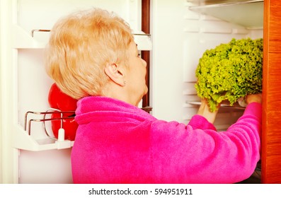 Senior Woman Taking A Green Lettuce From Fridge