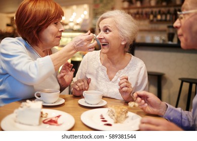 Senior Woman Taking Off Whipped Cream From Her Friend Nose