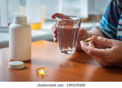 Senior Woman Is Taking Omega-3 Medicine Capsule. Female Hands Holding Vitamin D Supplement And Glass Of Water. 