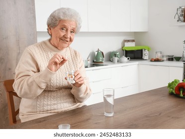 Senior woman taking pills in kitchen - Powered by Shutterstock