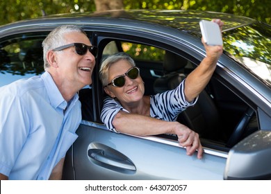 Senior woman taking selfie with man by car - Powered by Shutterstock