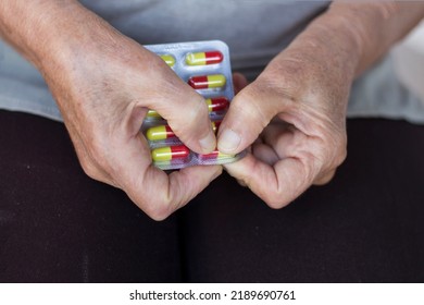 Senior Woman Taking A Tablet From A Dispanzer. Elderly Woman Taking A Pill From Table. 