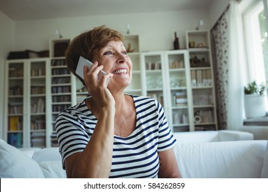 Senior Woman Talking On Mobile Phone In Living Room At Home