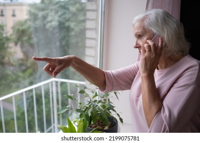 Senior woman talking on phone listening and hearing to rumor or gossip standing at home near window - Shutterstock ID 2199075781