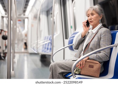 Senior woman talking on phone while sitting inside subway train. - Powered by Shutterstock