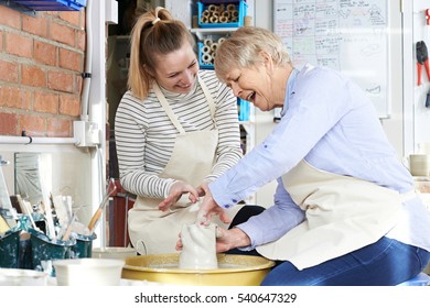 Senior Woman With Teacher In Pottery Class