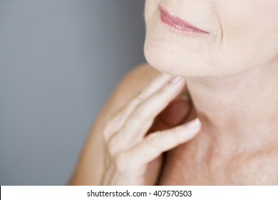 A senior woman touching her neck