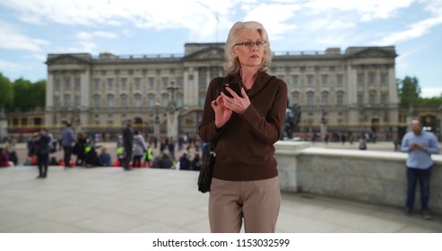 Senior Woman Tourist Checking Phone Map Or Rideshare App On Mobile In London