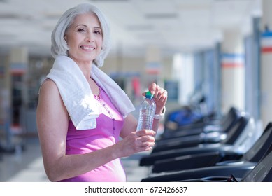 Senior Woman With Towel And Water At Gym