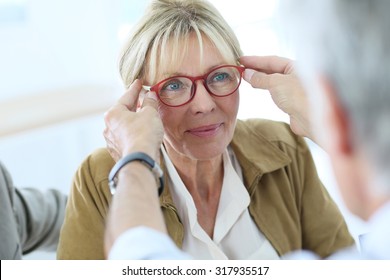 Senior woman trying new eyeglasses on, optical store - Powered by Shutterstock