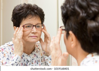 Senior Woman Trying On New Glasses And Looking At Herself In The Mirror
