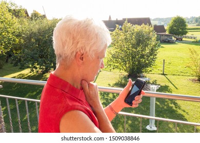 Senior Woman Trying To Read A Message In The Sun On A Cell Phone