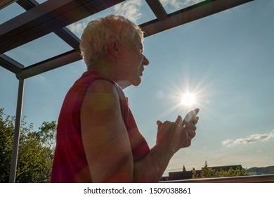 Senior Woman Trying To Read A Message In The Sun On A Cell Phone