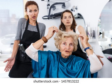 Senior Woman Unpleasantly Surprised By Haircut From Young Women Hairdressers Expressing Regret In Salon