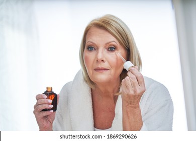 Senior woman using anti wrinkle serum in the bathroom - Powered by Shutterstock