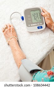 Senior Woman Using An Automatic Blood Pressure Cuff  To Monitor Her Health At Home.