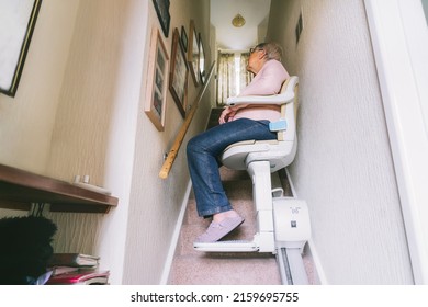 Senior woman using automatic stair lift on a staircase at her home. Medical Stairlift for disabled people and elderly people in the home. Selective focus