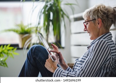 Senior Frau, die zu Hause digitale Tablette benutzt. Die Nutzung von Technologie durch ältere Menschen.