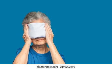 Senior Woman Using Hot Compress Gel On Eyes While Standing On A Blue Background. Nasolacrimal Duct Obstruction. Cataract Disease, Etc. Space For Text. Aged People And Healthcare Concept