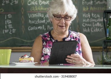 Senior Woman Using An Ipad/tablet In A Cafe