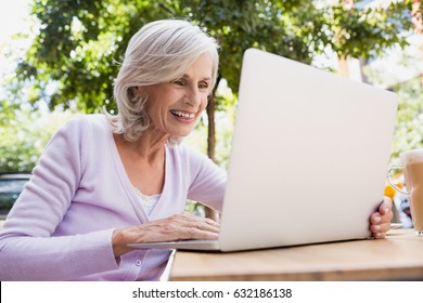 Senior woman using laptop in outdoor cafÃ© on a sunny day - Powered by Shutterstock