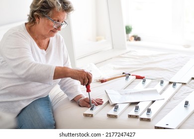 Senior Woman Using Screwdriver To Assemble Furniture