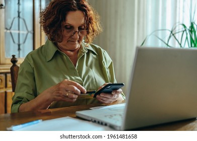 Senior woman using a smartphone and a credit card while exploring the internet and enjoining the online shopping - Shutterstock ID 1961481658