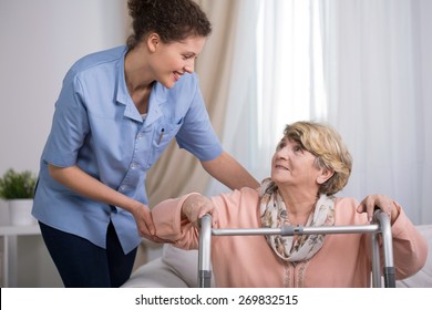 Senior woman using walking frame and supporting nurse