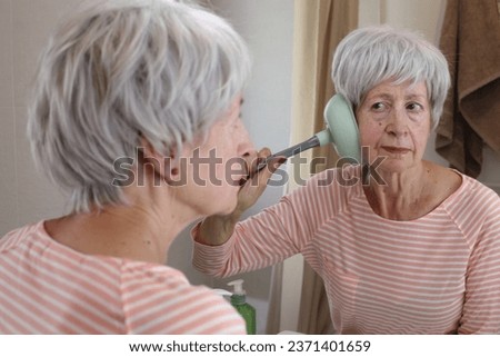 Senior woman using the wrong solution to clear her hearing canal 
