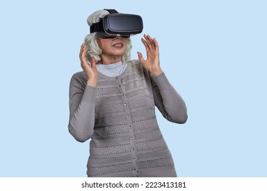 Senior Woman With Virtual Reality Headset On Blue Background. Old Lady Stunned By VR Experience.