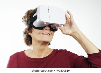 Senior woman with virtual reality headset is stunned by VR experience. Old woman smiled wearing in vr glasses on a white background. New technologies and old aged woman. - Powered by Shutterstock