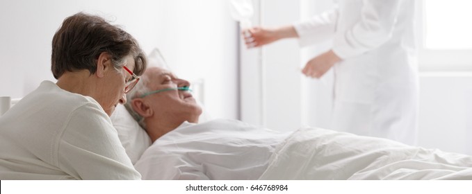 Senior Woman Visiting A Dying Man In Hospital