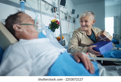 Senior woman visiting her husband in hospital, celebrating his birthday. - Powered by Shutterstock