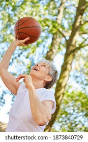 Senior Woman As A Vital Pensioner Playing Basketball For Fitness In The Garden In Summer