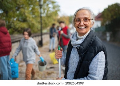 Senior Woman Volunteer With Team Cleaning Up Street, Community Service Concept