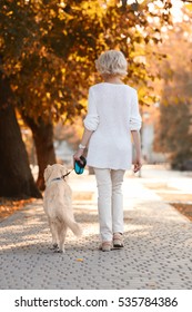 Senior Woman Walking With Dog In Park