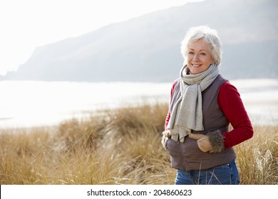 Senior Woman Walking Through Sand Dunes On Winter Beach - Powered by Shutterstock