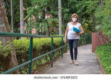 Senior Woman Walking To Yoga Class Wearing Protection Mask