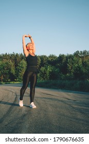 Senior Woman Warming-up Stretching Before Running Jogging On The Road. Vertical Image. Real Life Moments. 