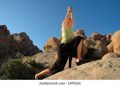 Senior Woman In Warrior Pose Outdoors On Large Boulders.