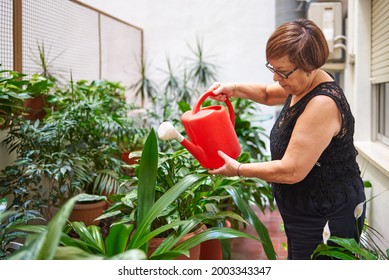 A senior woman waters the potted plants in her yard - Powered by Shutterstock