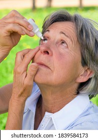 Senior Woman Wearing A Blue Shirt Using Eye Drops Out In The Field