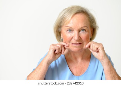 Senior woman wearing blue shirt while showing her face, effect of aging caused by loss of elasticity, close-up