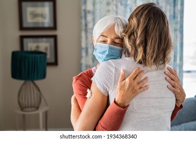 Senior Woman Wearing Face Mask Hugging Immunized Daughter After Covid-19 Vaccination Shot. Elderly Grandmother Hugging Adult Granddaughter After Covid Vaccine Jab. Immunity And End Of Covid19 Pandemic